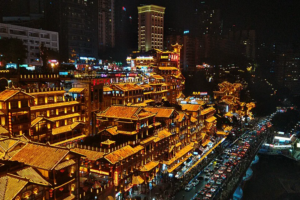 Hongya Cave glowing at night above a busy Chongqing street