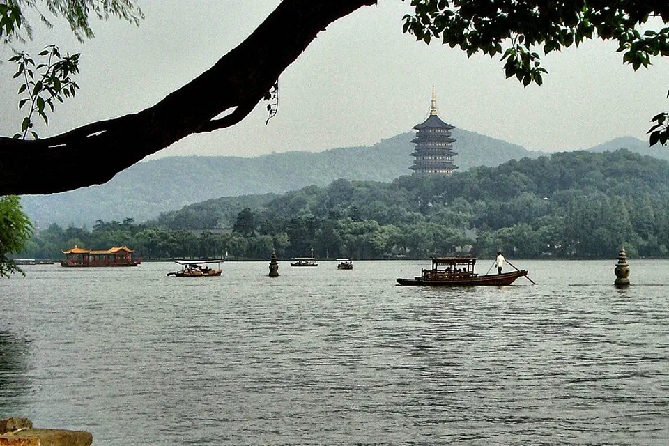 Boats crossing West Lake with Leifeng Pagoda on the wooded ridge in Hangzhou