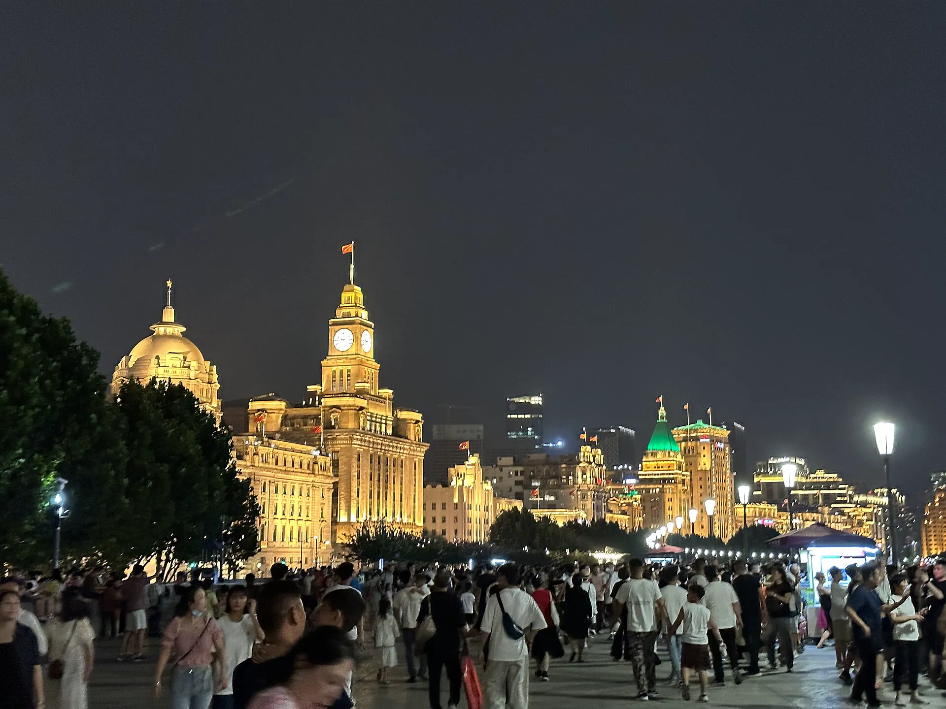 Crowded Bund promenade and illuminated historic buildings at night