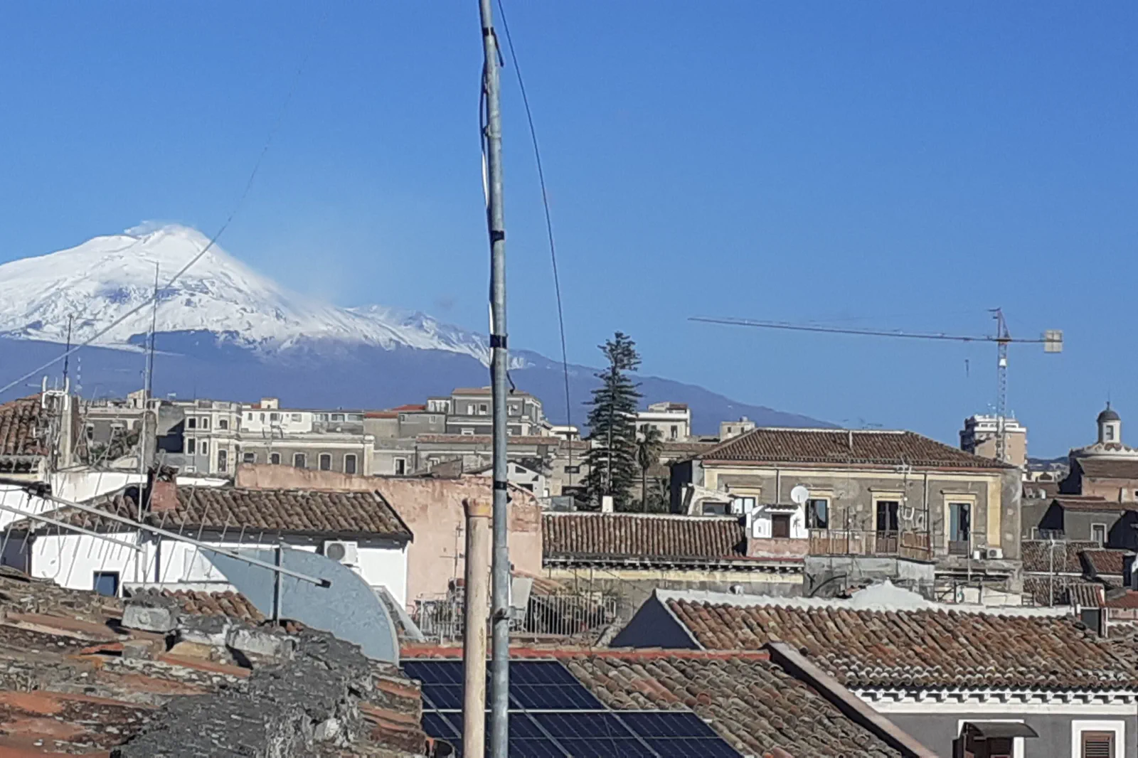 Mount Etna rising behind the city and rooftops of Catania