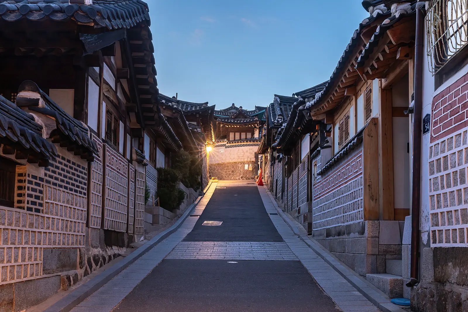 Hanok rooftops and Seoul skyline from a Bukchon lane at blue hour