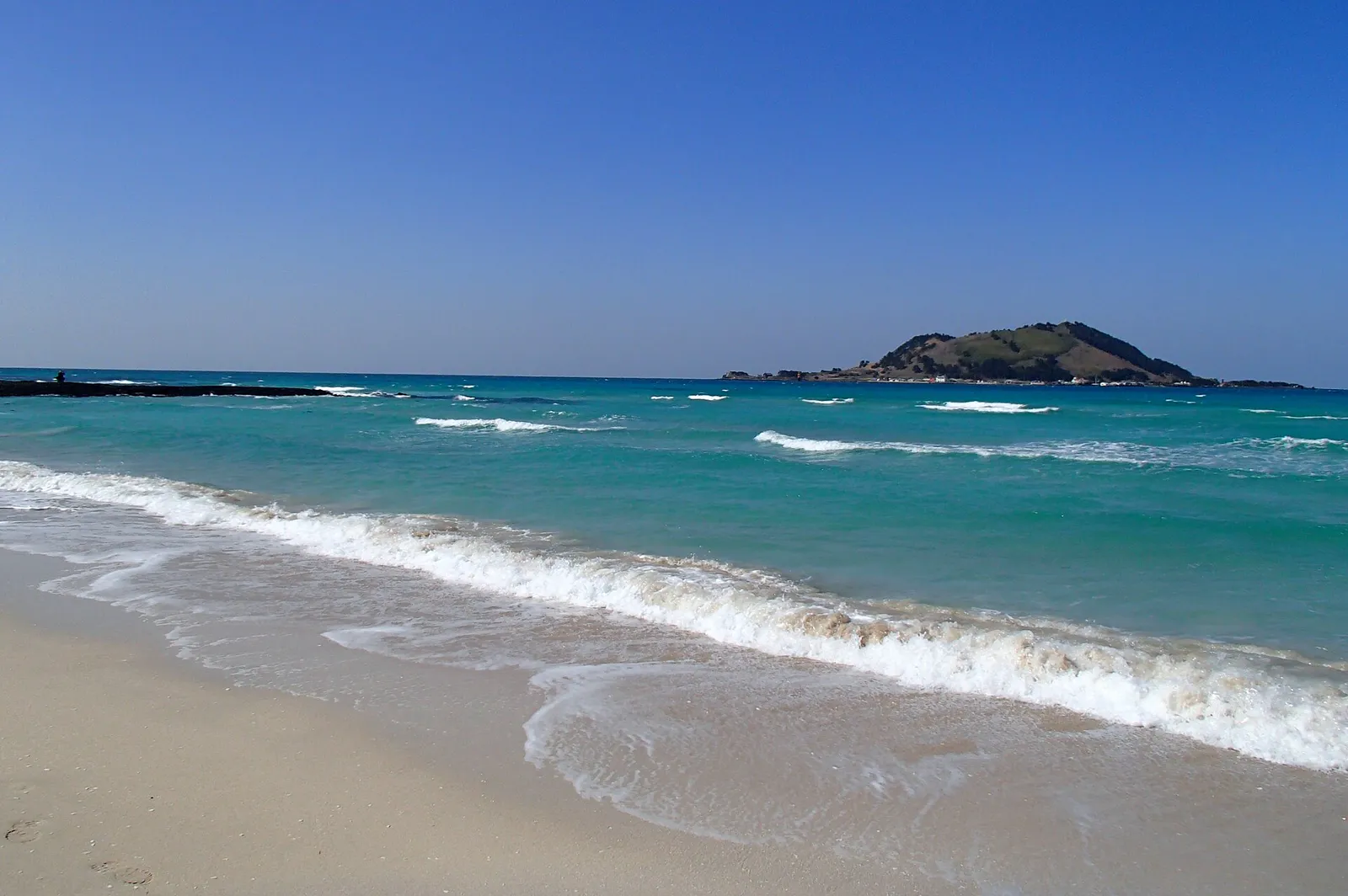 Clear water, pale sand and dark volcanic rock at Hyeopjae Beach