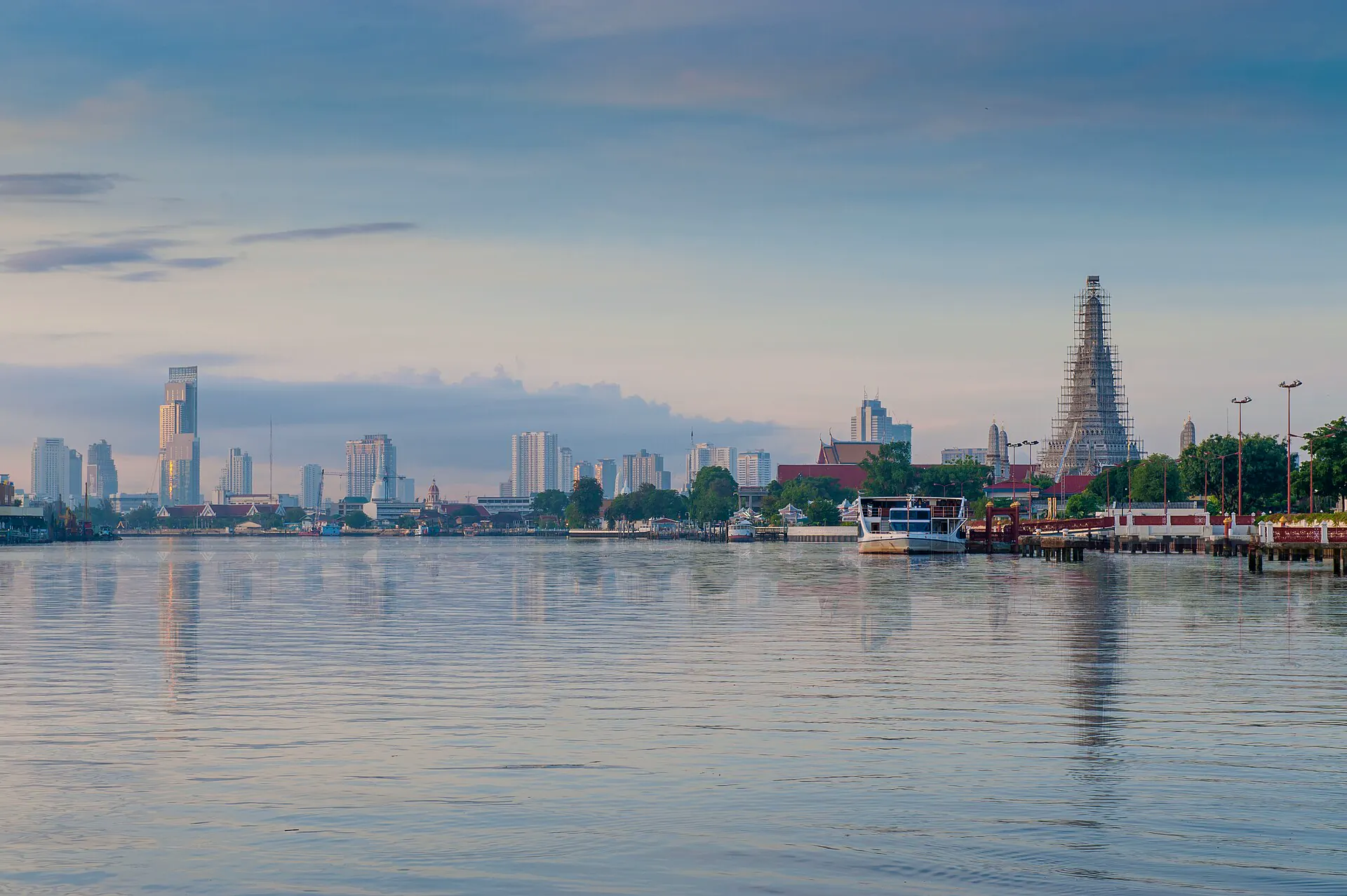 Wat Arun beside the Chao Phraya with Bangkok towers beyond