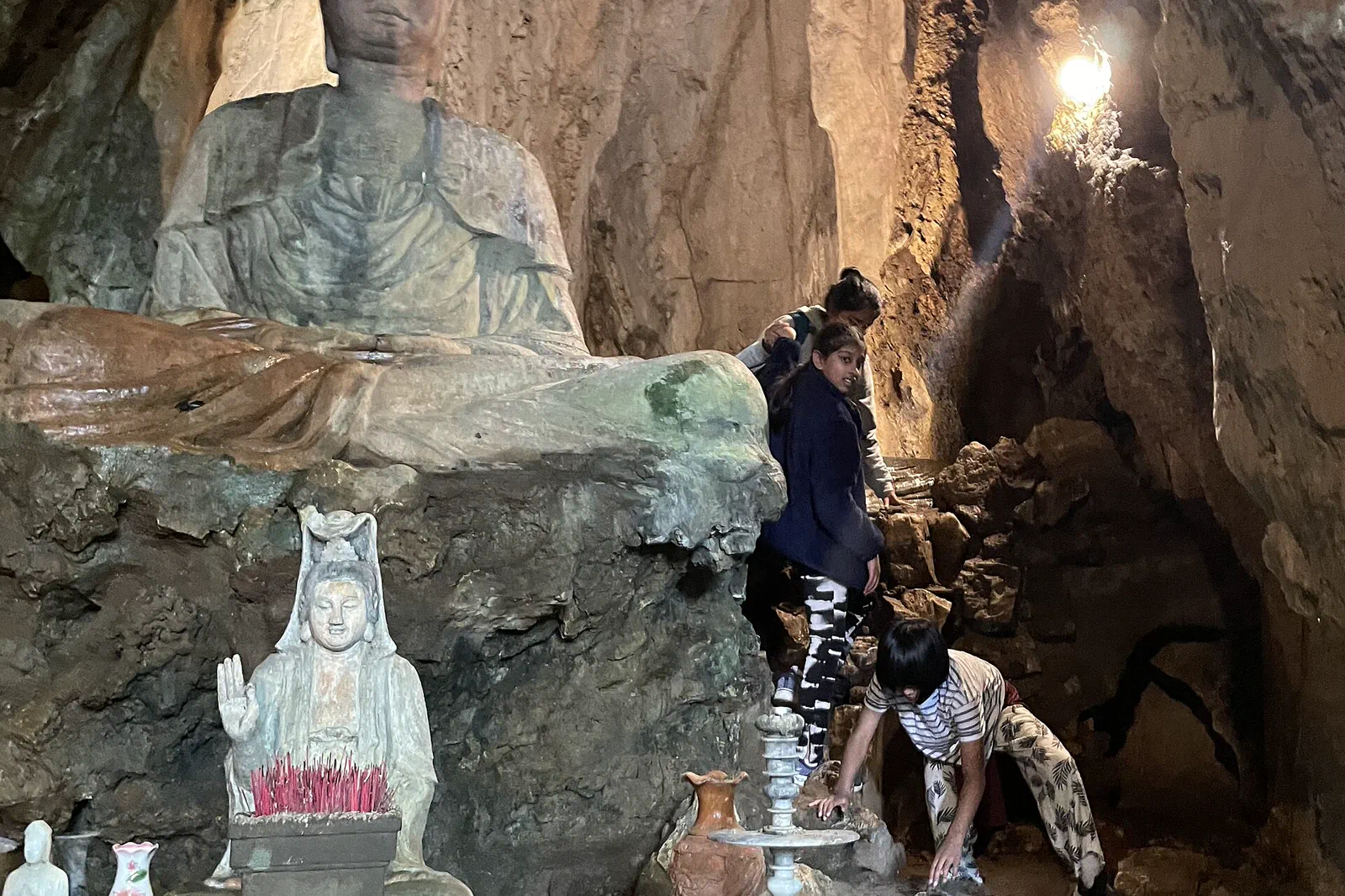 Cave shrine, stone statues and visitors inside the Marble Mountains