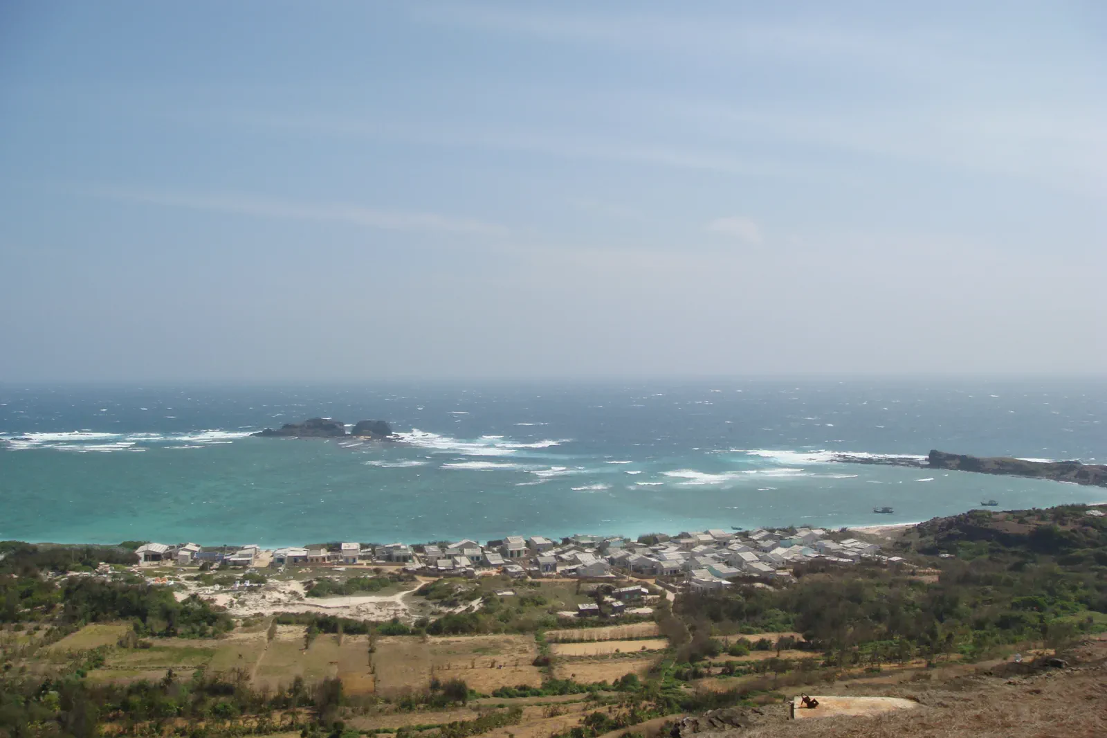 Coastal village and turquoise sea seen from the hills of Phu Quy Island